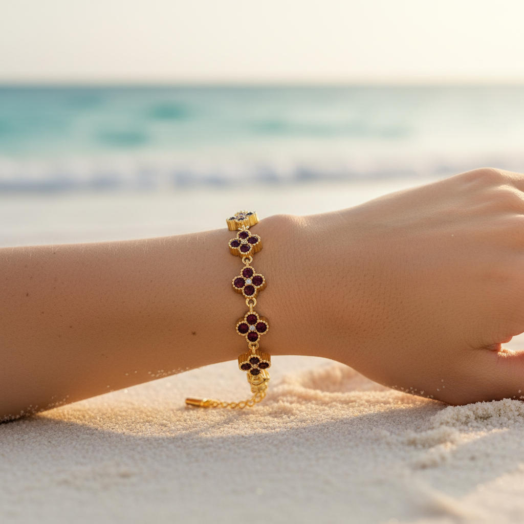 Bracelet chaîne dorée maillons trèfles pavé cristaux bordeaux grenat – lifestyle plage
