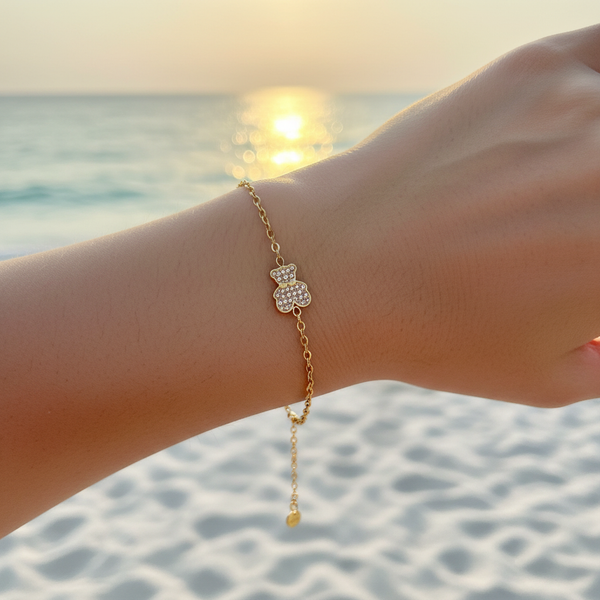 Bracelet chaîne fine dorée charm ourson pavé cristaux champagne – lifestyle plage