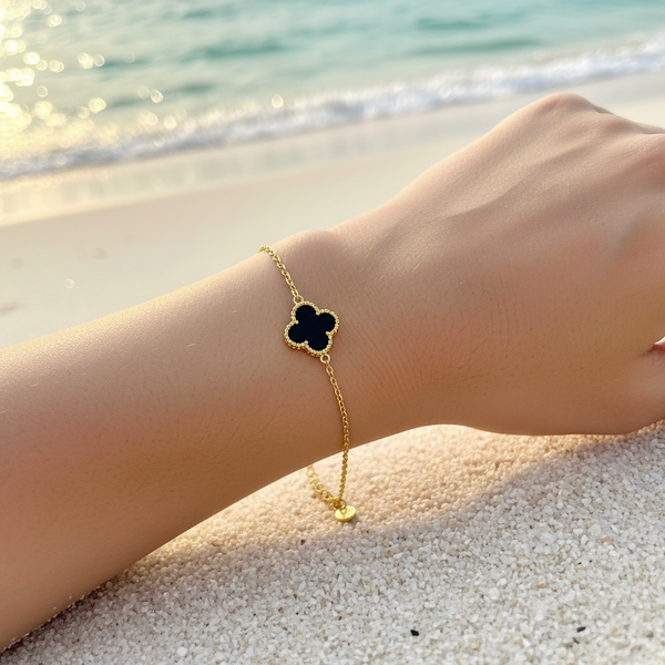 Bracelet chaîne fine dorée charm trèfle émail noir mat contour doré perlé – lifestyle plage