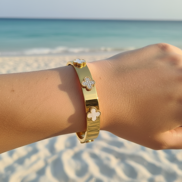 Bracelet jonc large doré & trèfles alternés nacre/pavé/nacre – lifestyle plage