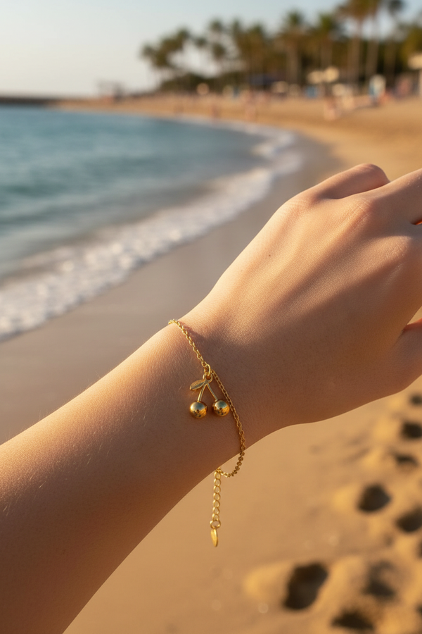 Femme portant bracelet chaîne dorée charm cerise plage