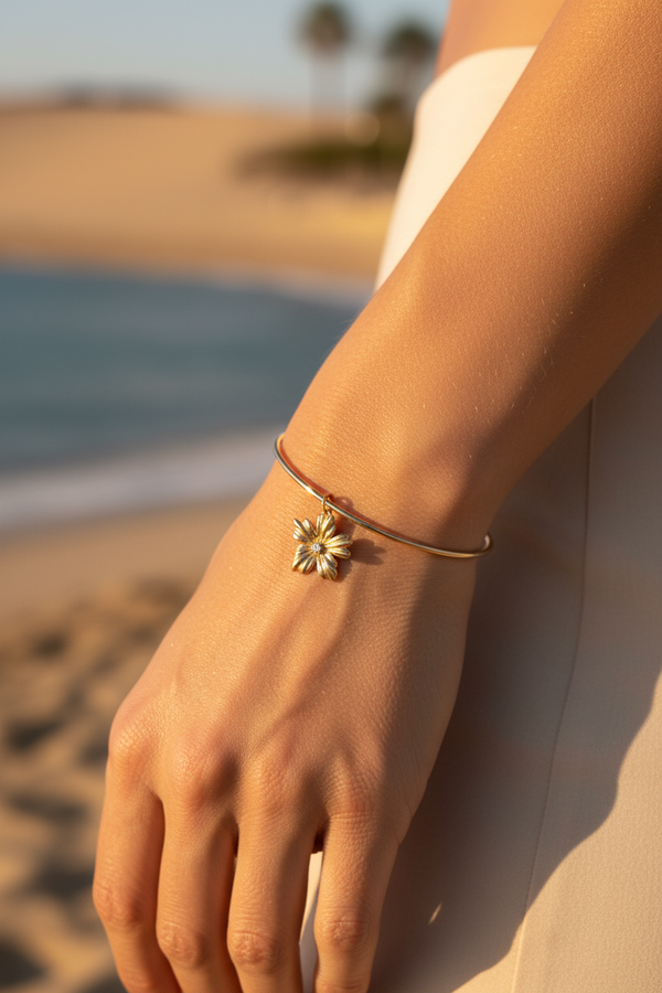 Femme portant bracelet jonc doré charm marguerite plage